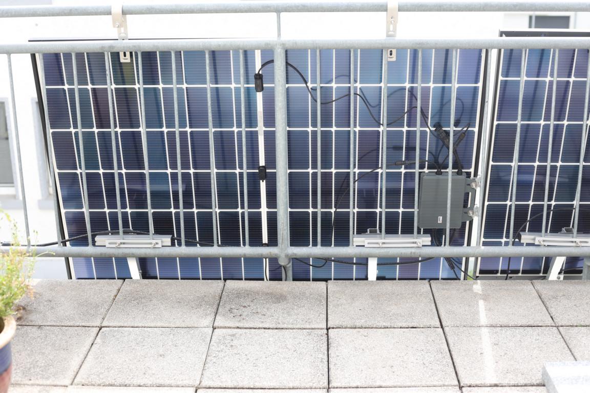 Die TSUN M800 Wifi Wechselrichter ist mit zwei Solarmodulen verbunden und hängt am Balkongeländer mit den Modulen zusammen.